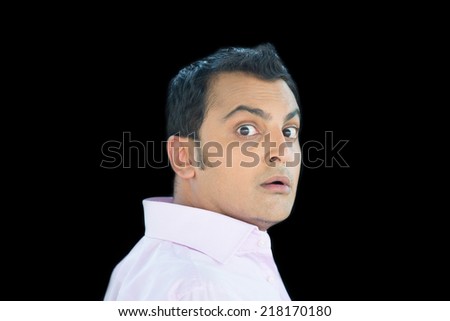 Closeup portrait of young scared, afraid, man, student,  employee, in pink shirt, full of fear, wide open eyes, guy on run, chased by someone, isolated black background