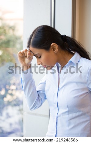 Closeup portrait, sad young woman in blue shirt, head on hand on window, really depressed, down about something, isolated city background. Negative emotion facial expression feeling body language