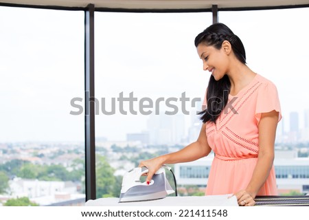 Closeup portrait of a young, attractive housewife, enjoying household work, ironing, engrossed, dignity of labor. Positive human emotions on isolated glass window indoor  background.