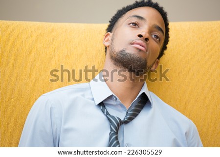 Closeup portrait, young disturbed, distressed employee in blue shirt striped tie, exhausted, resting head on seat, worried about something, about to collapse. Staring out in space
