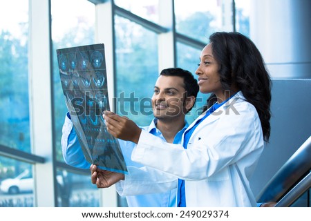 Closeup portrait of intellectual healthcare professionals with white labcoat, looking at full body x-ray radiographic image, ct scan, mri, isolated hospital clinic background. Radiology department
