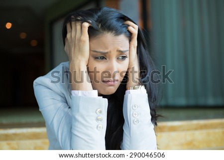 Closeup portrait, sad young woman in white gray suit sitting on stairs, really depressed, down about something, isolated indoors office background. Negative emotion facial expression feeling reaction