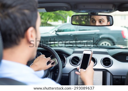 Closeup portrait, young man in blue polo shirt driving in black car and checking his phone, then shocked almost about to have traffic accident, isolated interior car windshield background