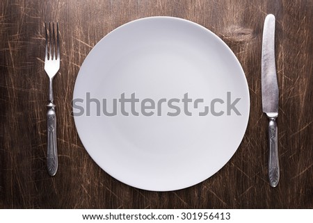 Empty plate, silverware over wooden table background. View from top with copy space.