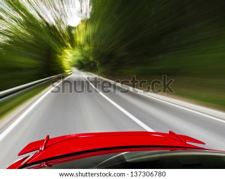 Rear view of a sports car driving fast on a winding road in the woods