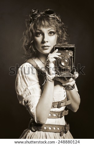 Beautiful steampunk girl in goggles with old camera. Old-fashioned.