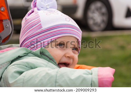 Picture of a little girl sitting in a wheelchair. The child looks at mom and laughs. Mom is not in the frame