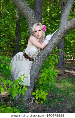 Beautiful blond woman in evening dress in the forest
