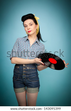 Beautiful pin-up woman with record in her hands on blue background