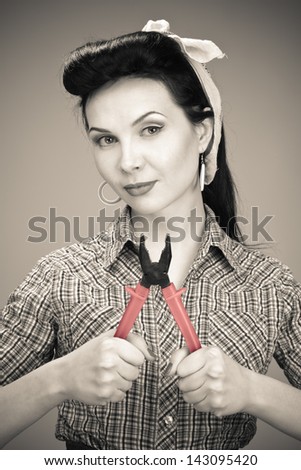 Pin-up girl in check shirt with pliers