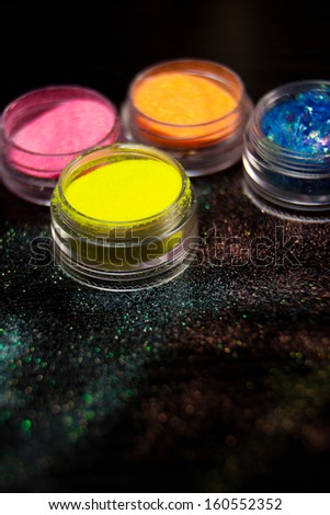 Colorful powder for nails on black background