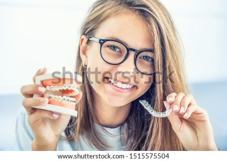 Dental invisible braces or silicone trainer in the hands of a young smiling girl. Orthodontic concept - Invisalign. Stock foto © 