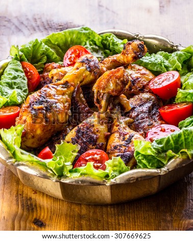 Grilling. Grilled chicken. Grilled chicken legs. Grilled chicken legs, lettuce and cherry tomatoes. Traditional cuisine. Mediterranean cuisine.