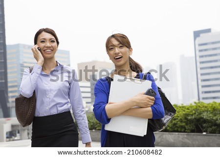Business woman who walk side by side while talking happily