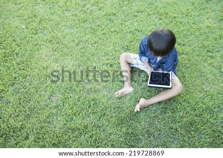 Boy to operate the tablet on the lawn
