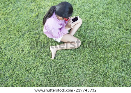 Girl to operate the smart phone on the lawn