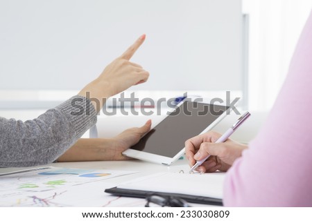 Woman pointing at the white board while having an electronic tablet