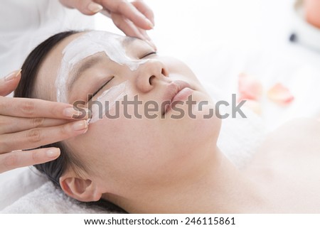 The esthetician applying beauty mask a female face