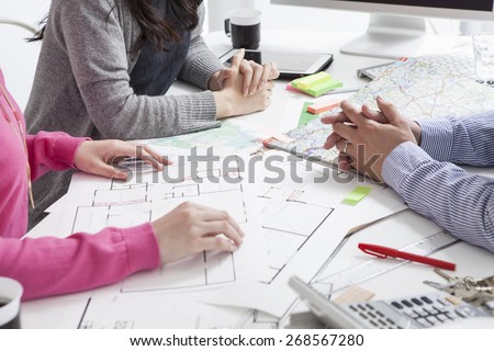 Hand pointing architectural blueprint. over blurred architectural blueprint of office building