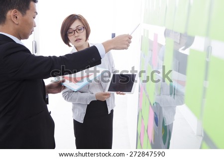 Young professionals discussing ideas written on sticky notes