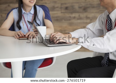 Two happy businessmen working together on a laptop sitting at a table in the office