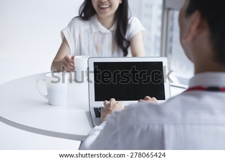 Happy Young Business Couple Watching Something at Laptop Computer on Top of the Office Table.
