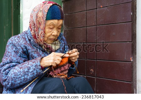 Hanoi, Vietnam November 07, 2014 a 92-year-old woman is sitting to knit wool scarf on a street.