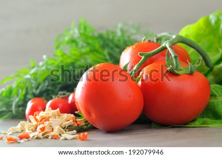 Closeup of vegetable groceries on the wooden kitchen table - tomatoes, cherry tomatoes, carrots and lettuce