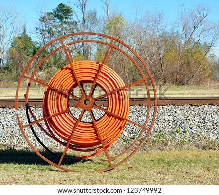 A Roll Of Orange Heavy Duty Industrial Cable On A Metal Roller Wheel