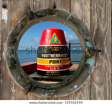 The  Southernmost Point In The Continental USA Buoy in Key West, Florida, as seen through a rustic old porthole.
