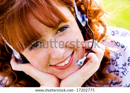 Close-up portrait of red-haired lovely young woman with headset outdoors