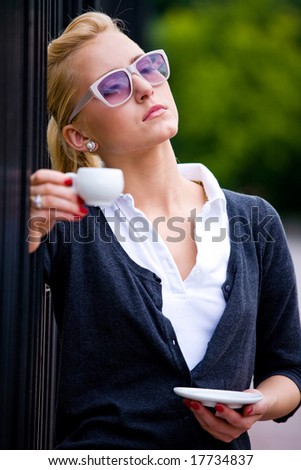 Blond lovely young woman drinking coffee outside