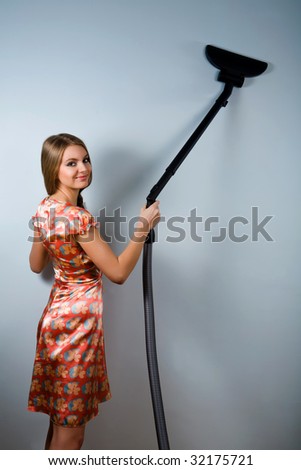 Funny attractive housewife with vacuum cleaner indoors