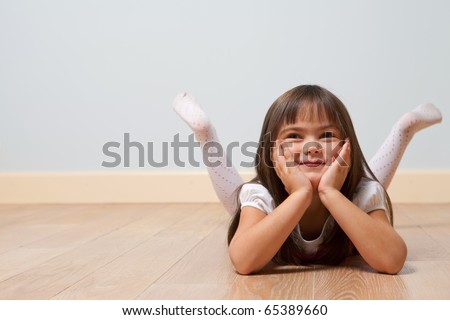 Funny portrait of lying cute girl on a wooden floor indoors