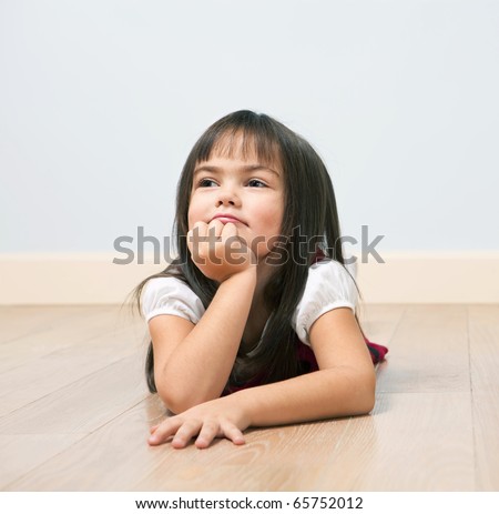 Funny portrait of lying cute girl on a wooden floor indoors