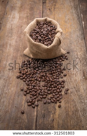 Roasted coffee beans in burlap sack, coffee beans in burlap bag on old wood panel