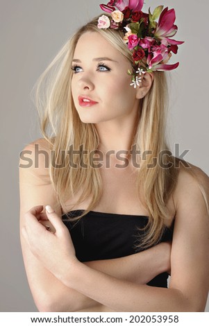 Young blonde lady with flower crown posing in a black crop top looking into the distance