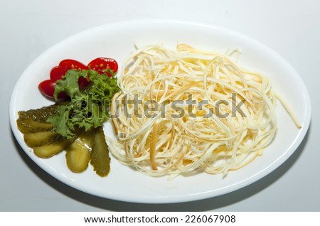 Smoked cheese with vegetables on white plate, vertical shot