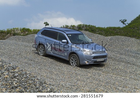 Ha Noi, Viet Nam - May 18, 2015: The Mitsubishi Outlander PHEV plug-in Hybrid CUV car running on the rocky gravel stones road in Vietnam