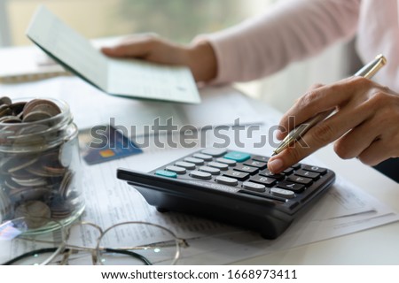 Young asian woman checking bills, taxes, bank account balance and calculating credit card expenses. Family expenses concept.