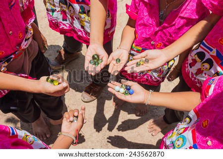 Children playing marbles, activity of student in Thailand.