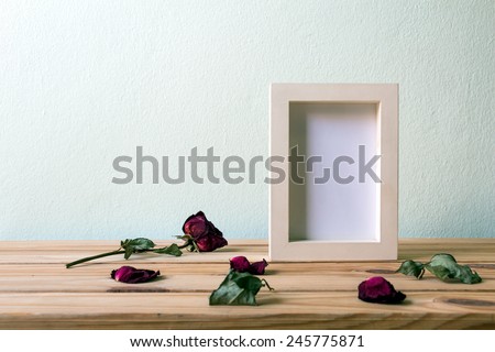 Still life with red rose and white photo frame on wooden table over grunge background, Valentine concept
