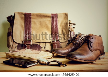 Still life with casual man, boots and bag on wooden table over grunge background