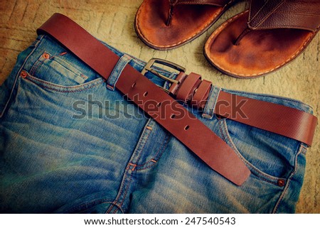 Still life with jeans and slippers on green carpet background