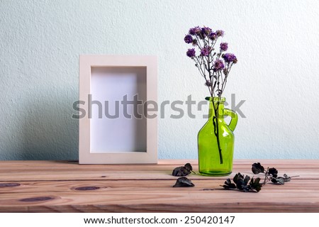 Still life with flowers and white photo frame on wooden table over grunge background, Valentine concept