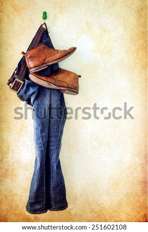 Still life with jeans and brown boots hanging over grunge background