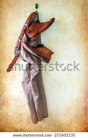 Still life with brown pants and boots hanging over grunge background