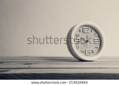 clock on wooden table over grunge background, black and white