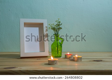still life with candle and photo frame on wooden table over grunge background, vintage style
