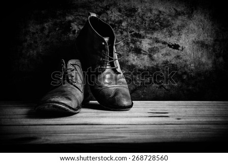 still life with boots on wooden table over grunge background, , black and white